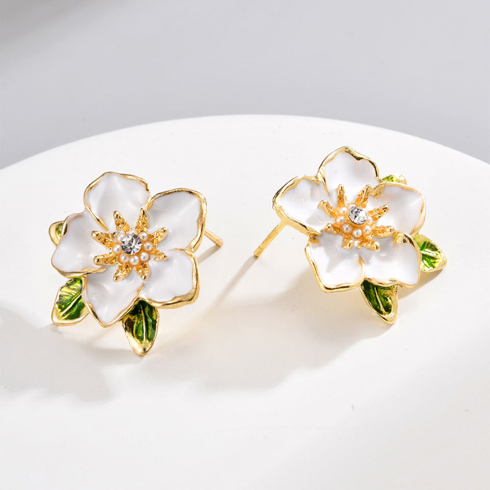 Elegant White Enamel Flower Stud Earrings – Gold-Toned Floral Statement Jewelry with Crystal Center and Green Leaf Accents