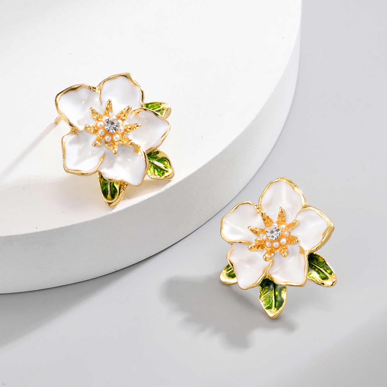 Elegant White Enamel Flower Stud Earrings – Gold-Toned Floral Statement Jewelry with Crystal Center and Green Leaf Accents